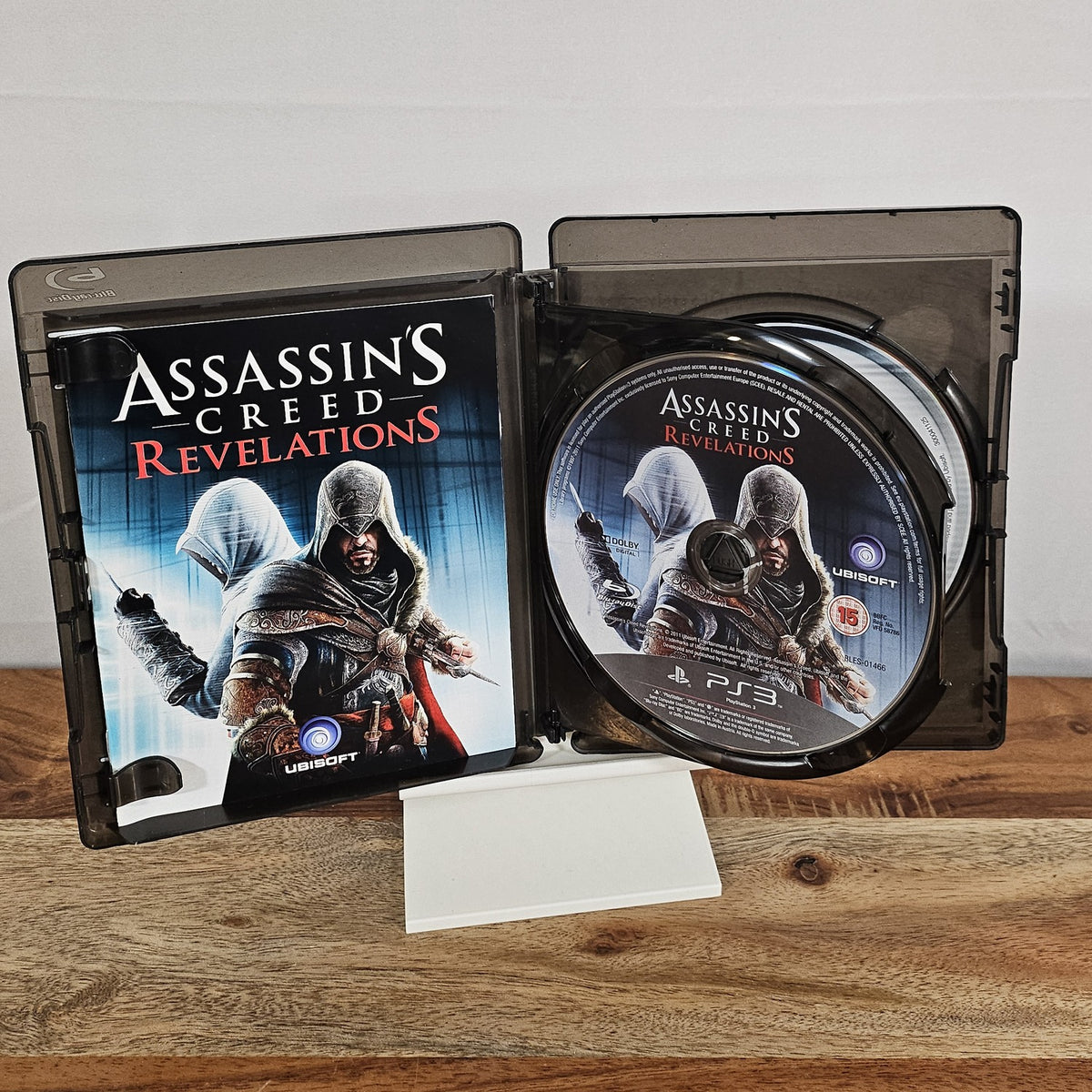 Assassin’s Creed Revelations für PlayStation 3 – geöffnete Originalhülle mit Spiel-Disc und Unterlagen