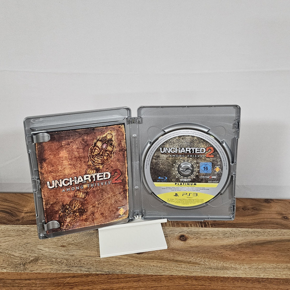 Uncharted 2: Among Thieves Platinum für PlayStation 3 – geöffnete Originalhülle dieses Exemplars mit Disc und Unterlagen