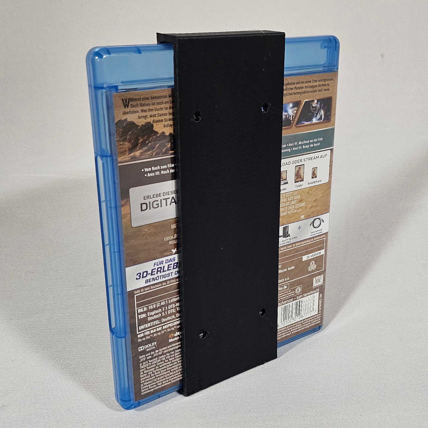 Gedrucktes Beispiel des Blu-ray-Hüllen-Wandhalters mit eingesetzter Blu-ray – Rückansicht
