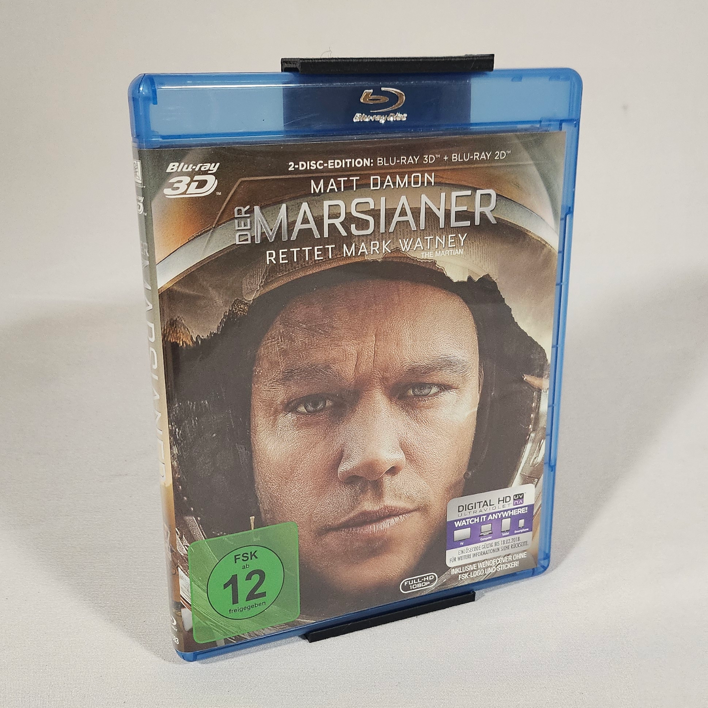 Gedrucktes Beispiel des Blu-ray-Hüllen-Wandhalters mit eingesetzter Blu-ray – Vorderansicht